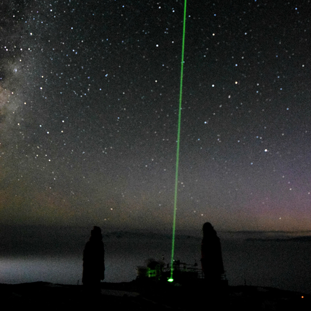 two people at night looking at a green laser