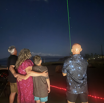 two people at night looking at a green laser