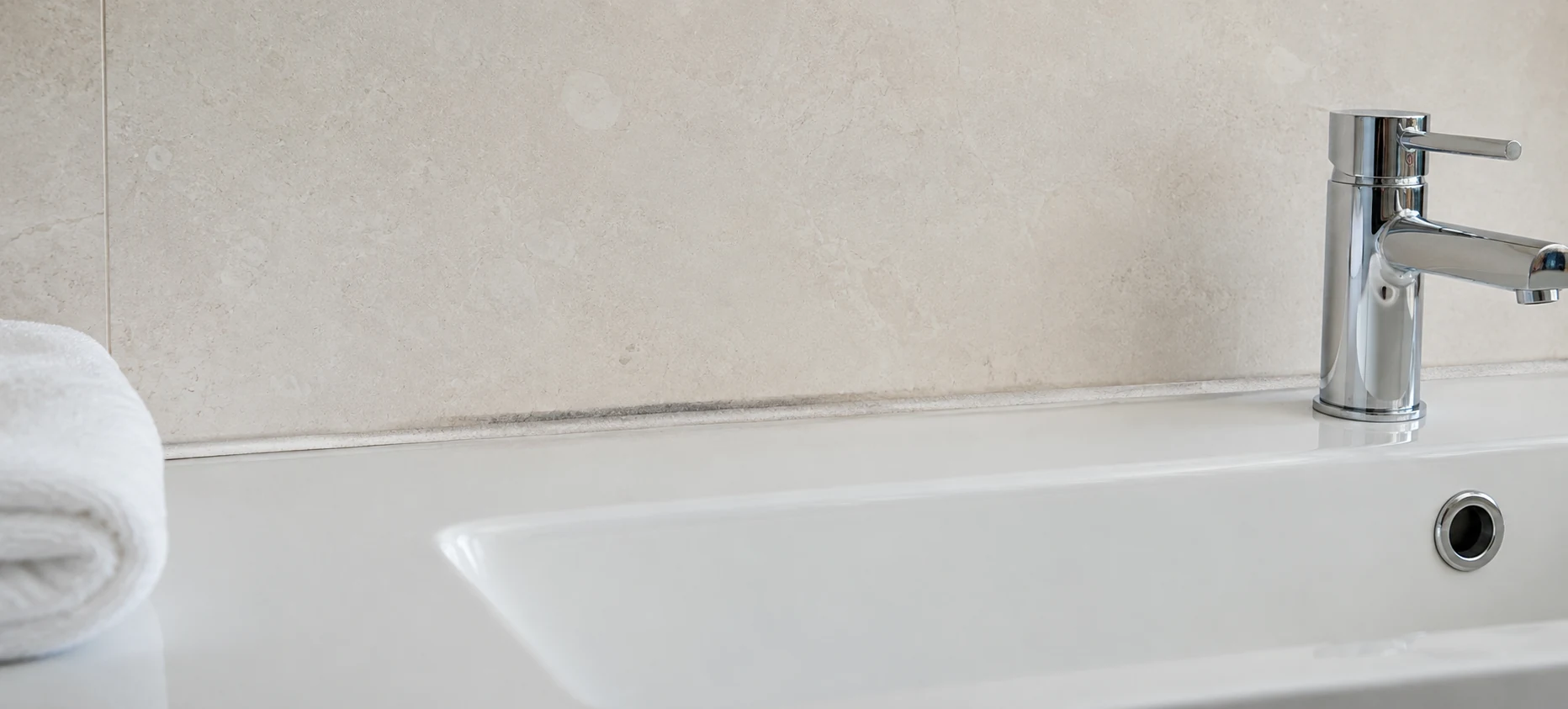 Joint de silicone noirci au raccord d'un lavabo d'hôtel
