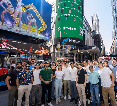Group of diverse people posing in front of Nasdaq building with large digital displays in New York.
