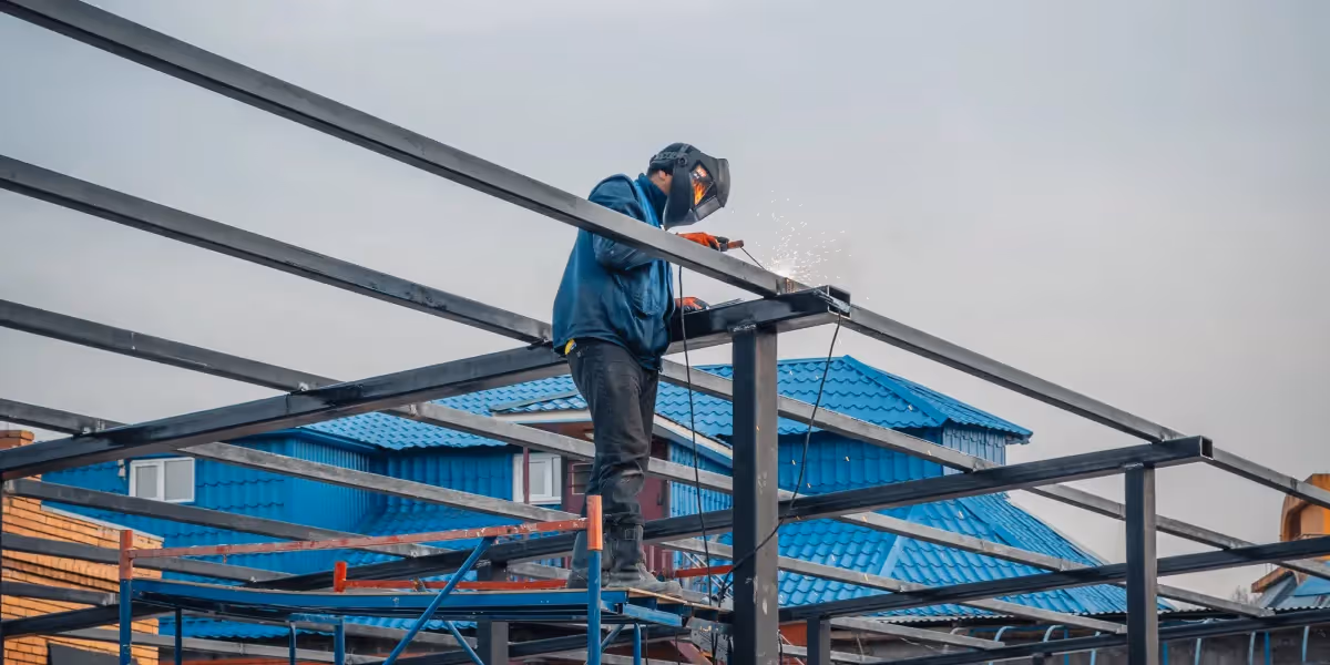 Welder on ladder working on metal