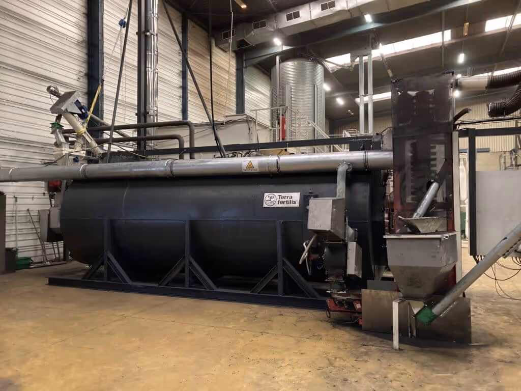 Large industrial machine labeled 'Terra Fertilis' inside a factory with metal pipes and ducts.