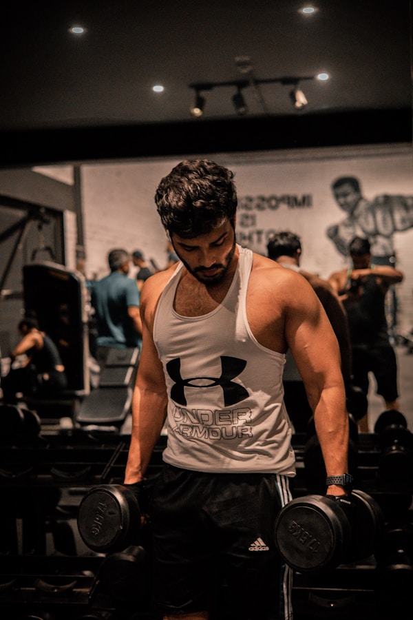 A muscular man lifts dumbbells at the gym.