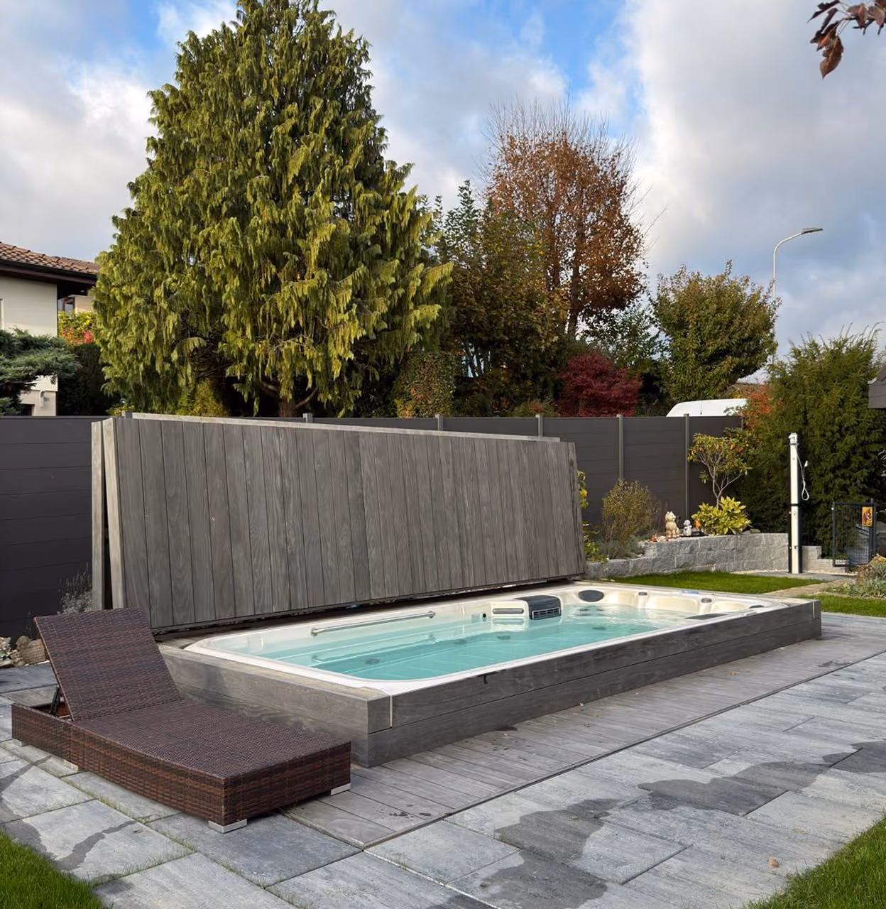 Swim Spa mit grauer Abdeckung im gepflegten Gartenbereich