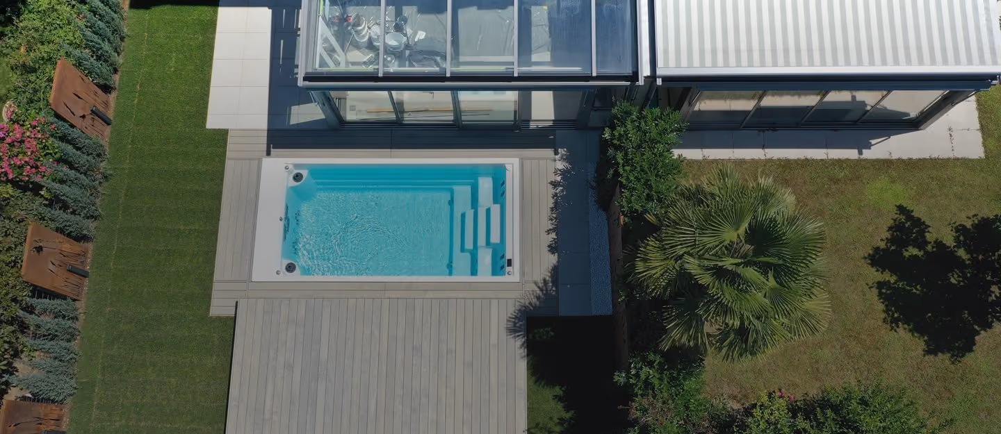 Fachmann und Kunde mit Swim Spa, Sauna und Gruenlandschaft im Hintergrund