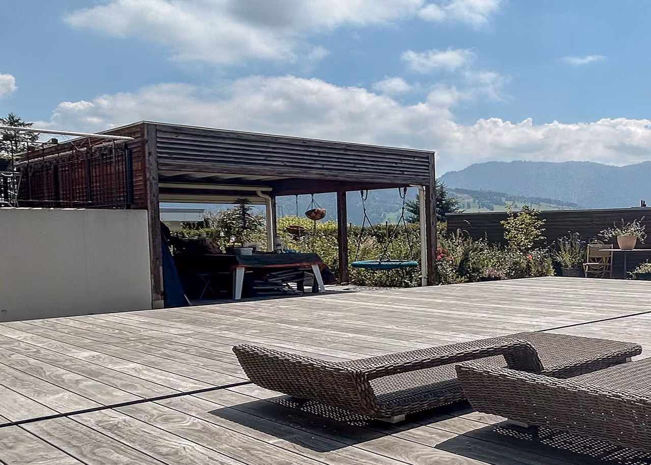 Holzpergola mit Lattendach auf einer Holzterrasse mit Rattanliegen und Bergpanorama, Aussenbereich von RR Variationen