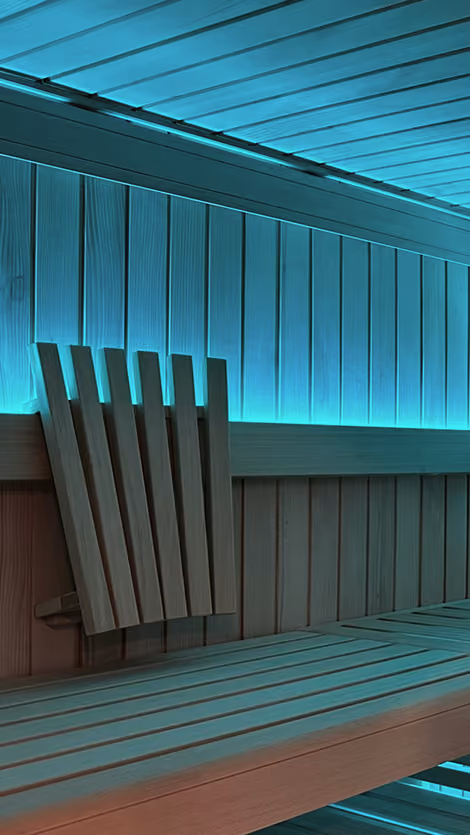 Innenraum einer Holzsauna mit blauer Ambientebeleuchtung entlang der Wände und der Decke.
