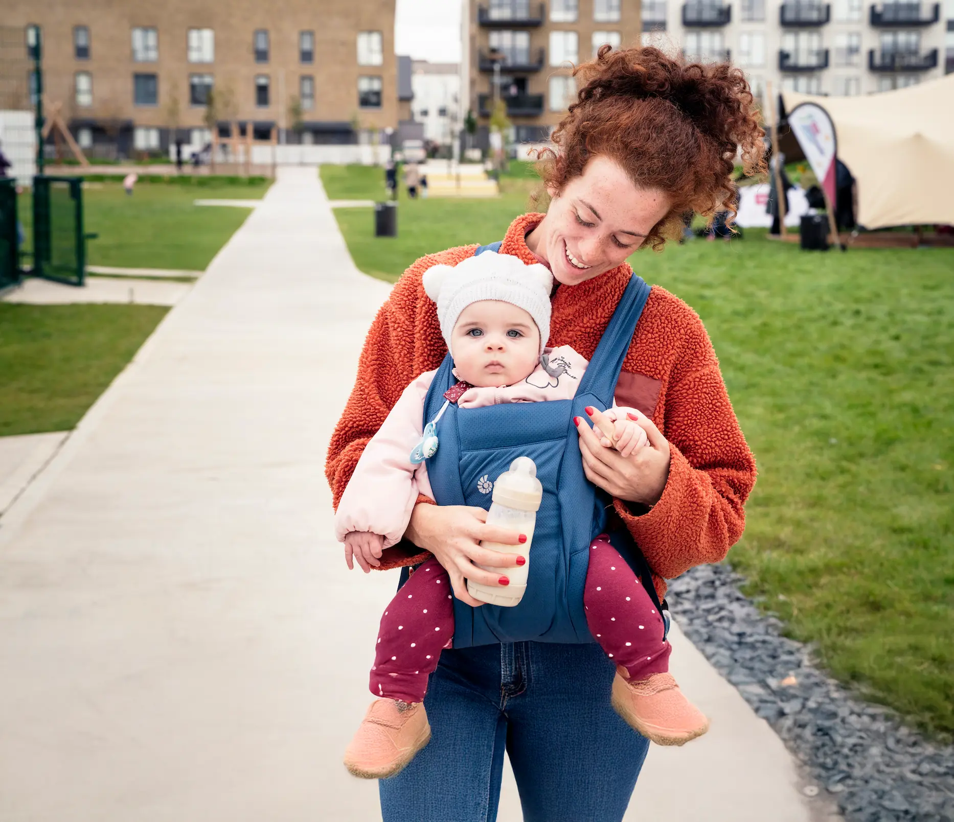 A woman holding a baby in a baby carrier.
