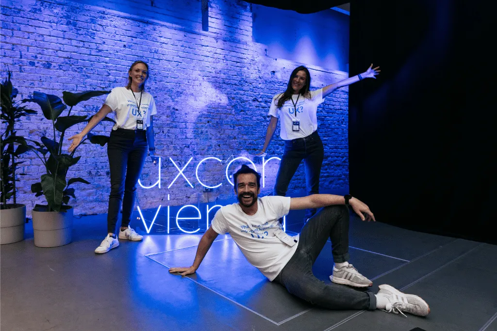 A picture of team from Userlytics posing in front of the uxcon vienna neon sign.