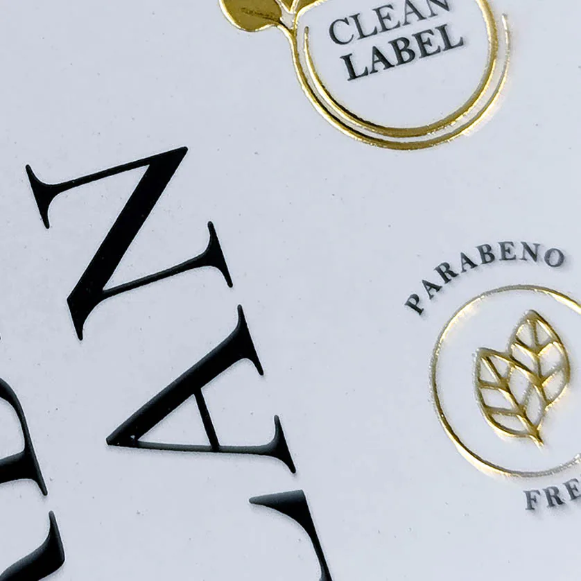 Detalhe de acabamento premium em Hot Stamping dourado sobre papel de alta gramatura.