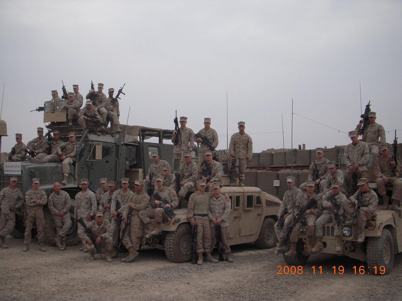 Military unit posing with tactical vehicles at field base