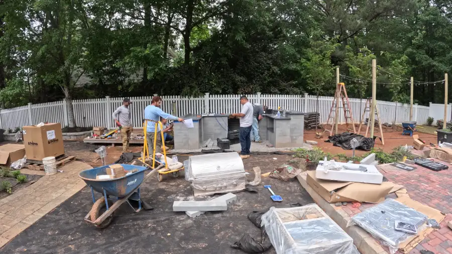 Outdoor kitchen builders installing appliances in backyard patio area