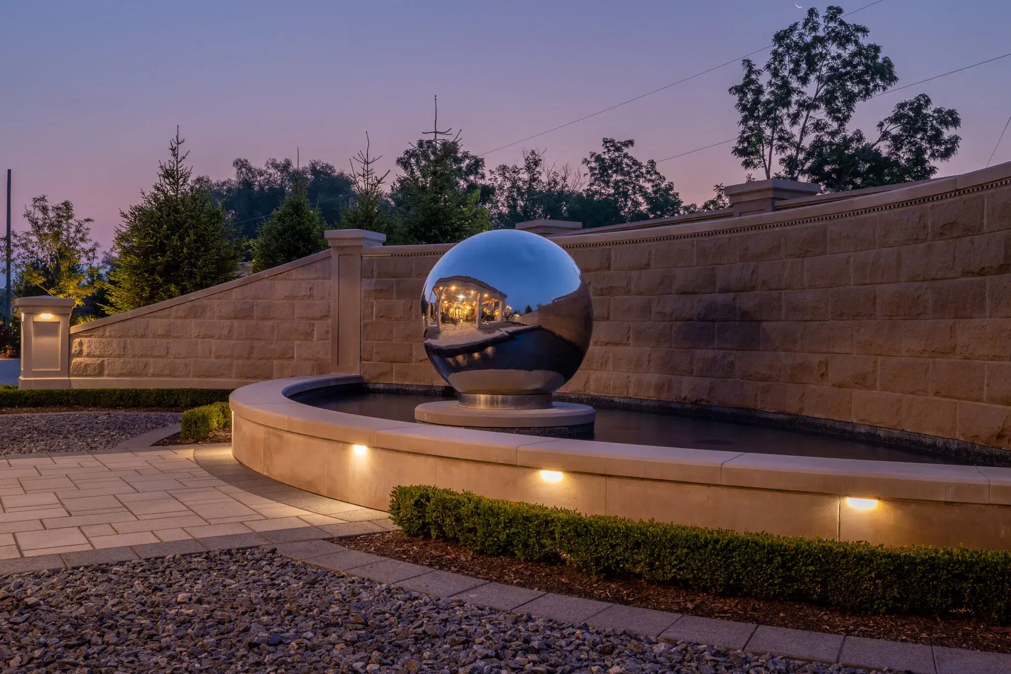 Landscape lighting around decorative fountain and stone retaining wall