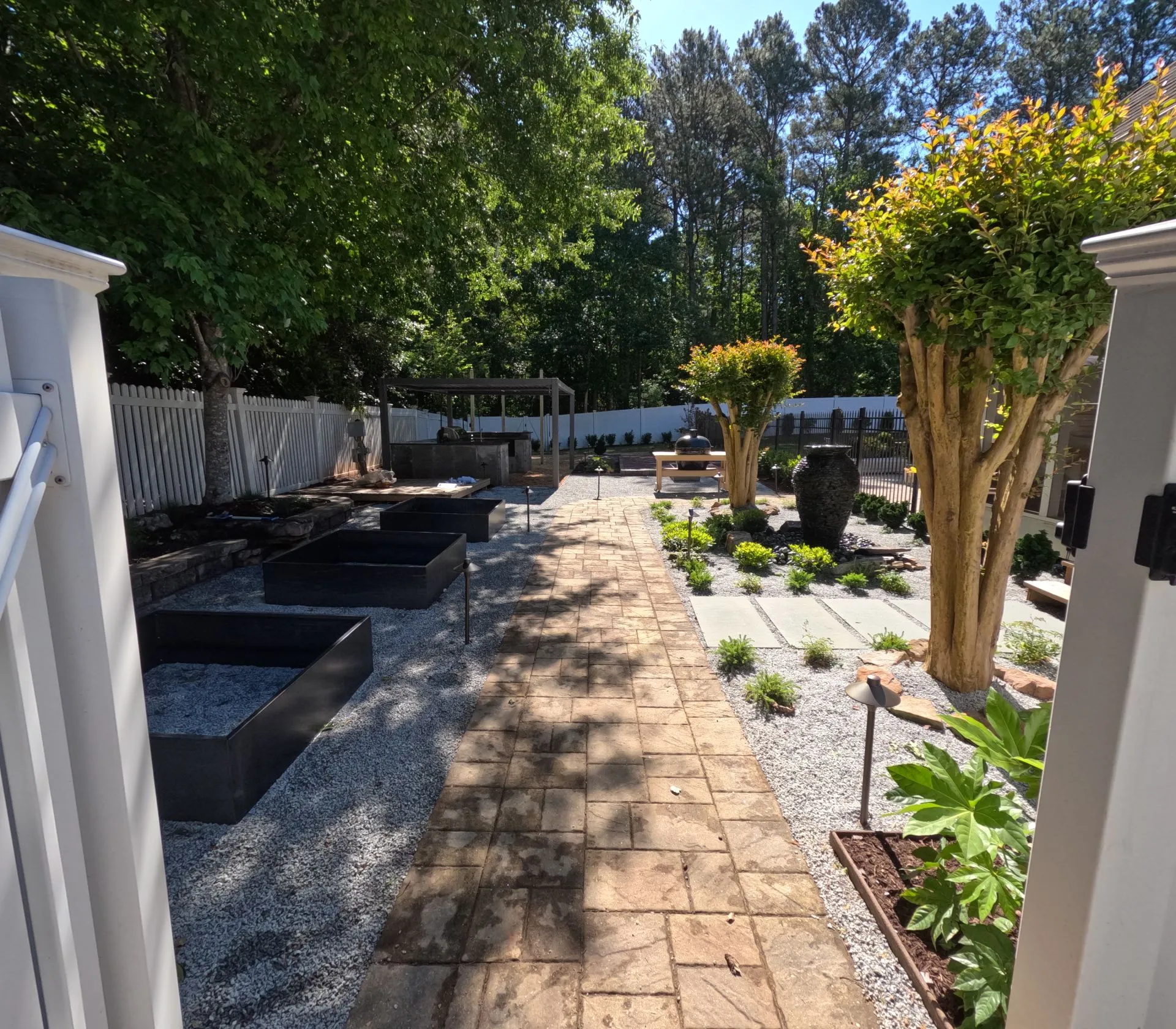 Backyard landscaping with brick courtyard, garden beds, and walkway