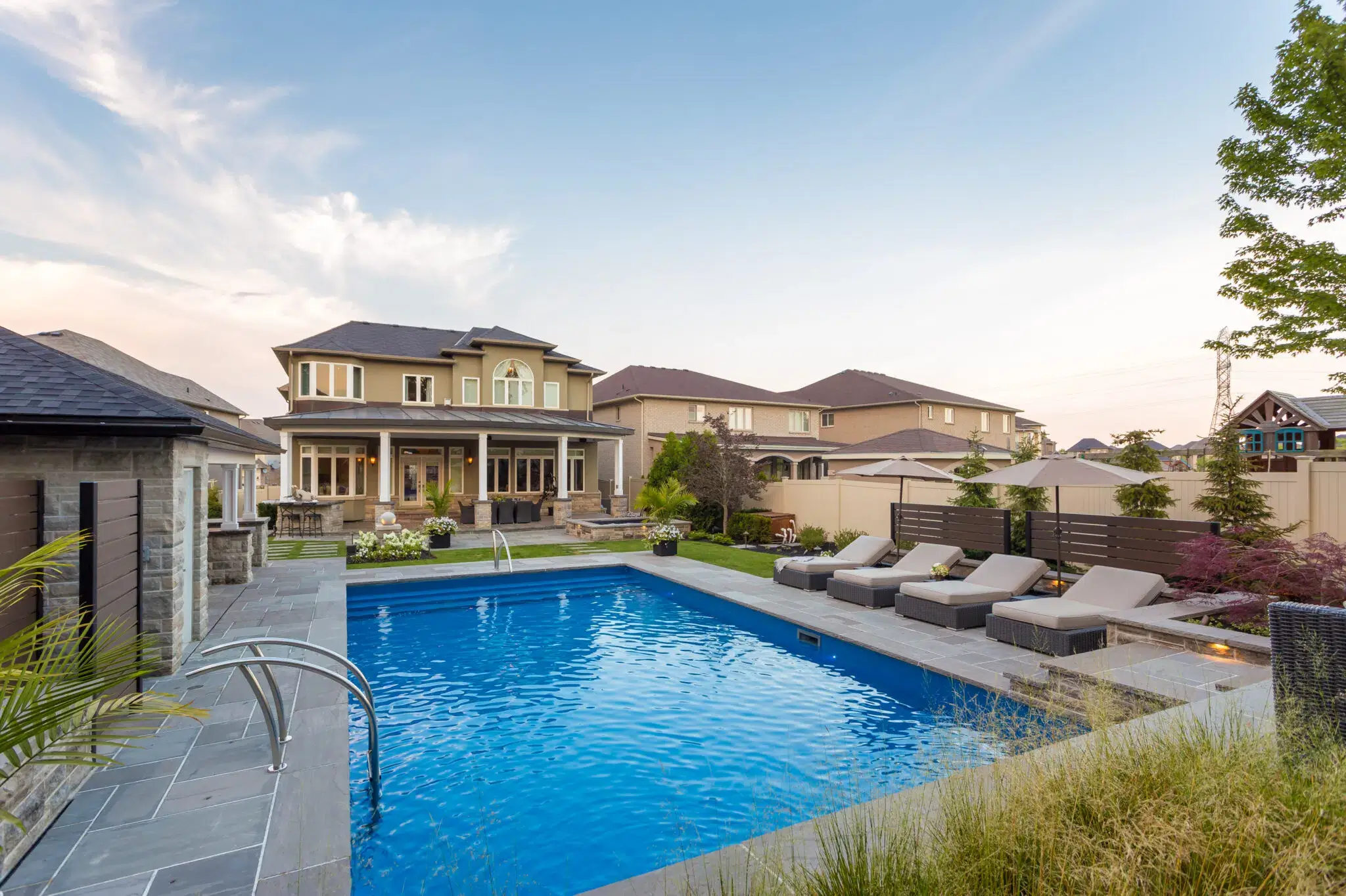 Residential landscape design with backyard pool and stone patio