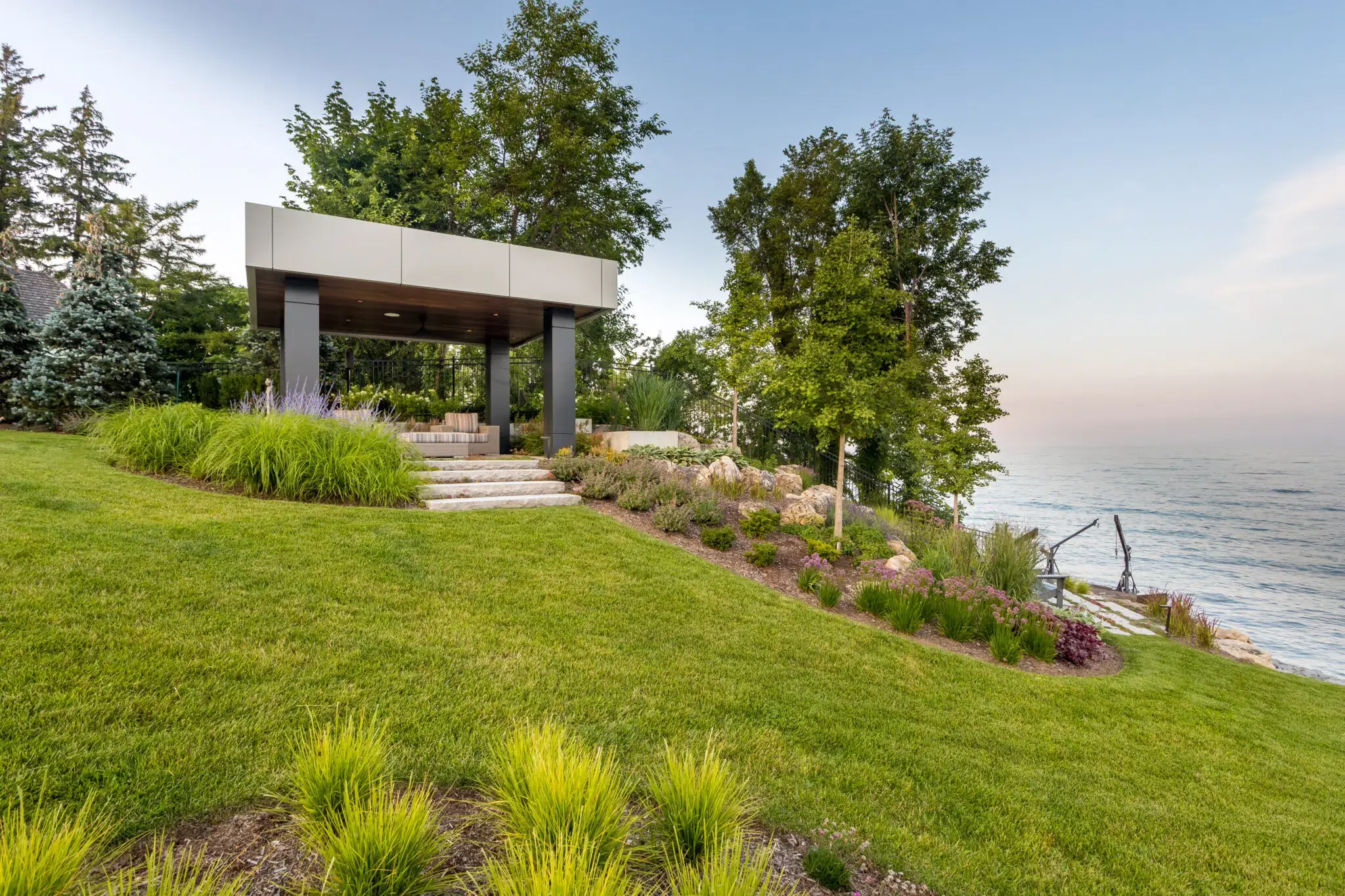 Lakeside garden landscaping with pavilion, trees, and flowering plants