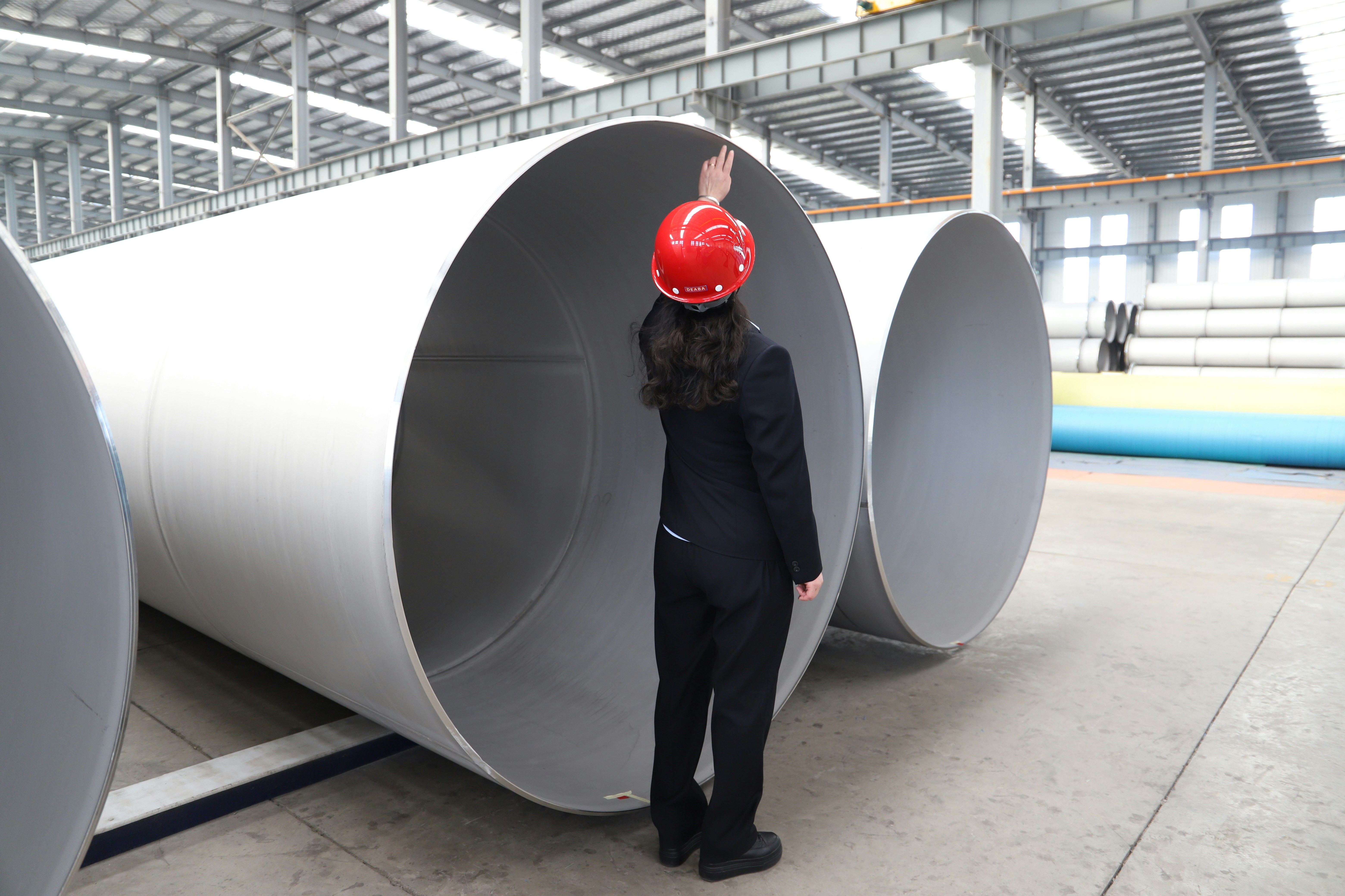 An inspector in a hard hat checking large steel pipes, illustrating reasonable assurance in CBAM verification
