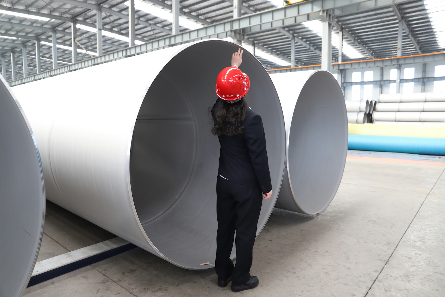 An inspector in a hard hat checking large steel pipes, illustrating reasonable assurance in CBAM verification