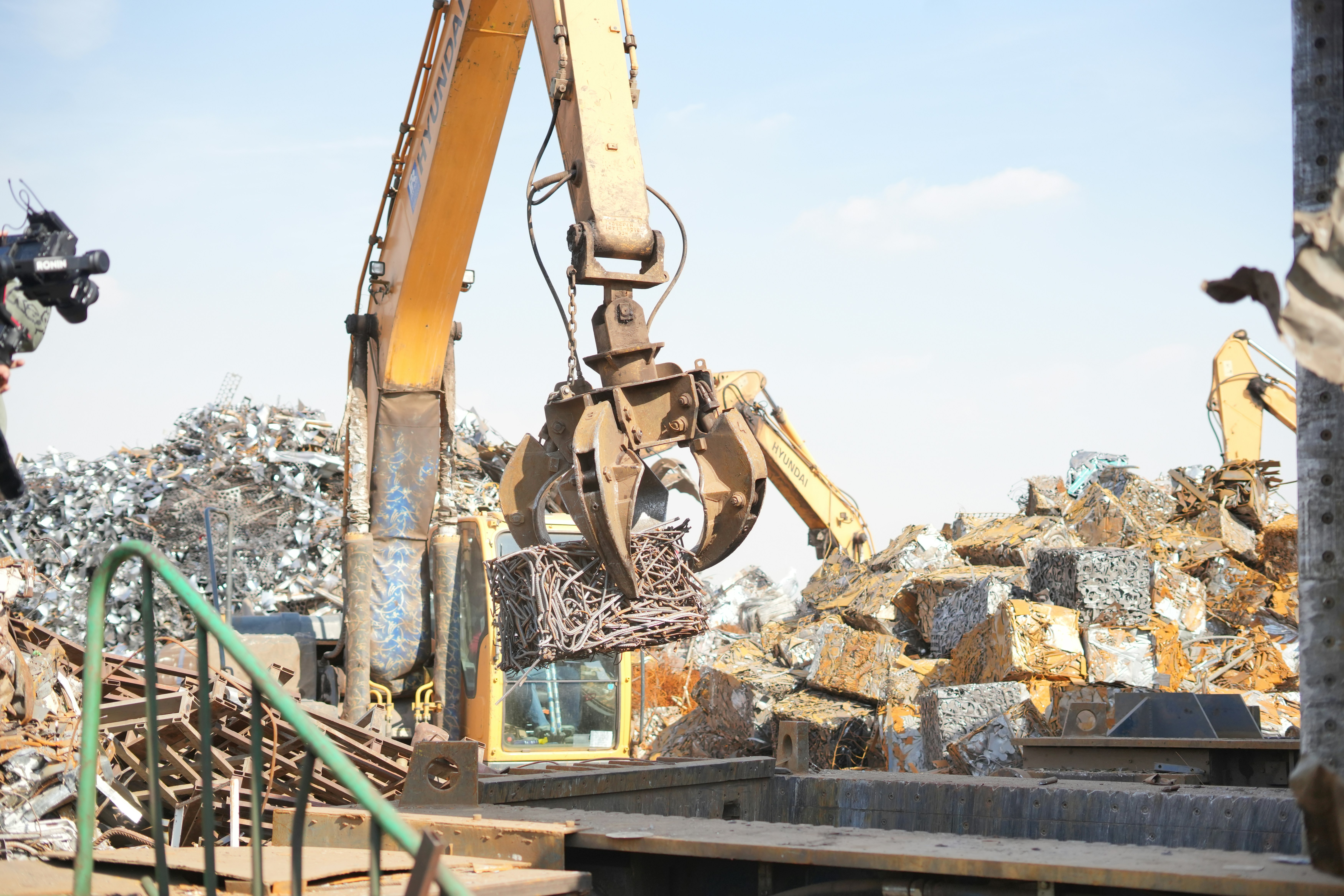An excavator grab handling scrap metal, which the Council's CBAM position brings into scope