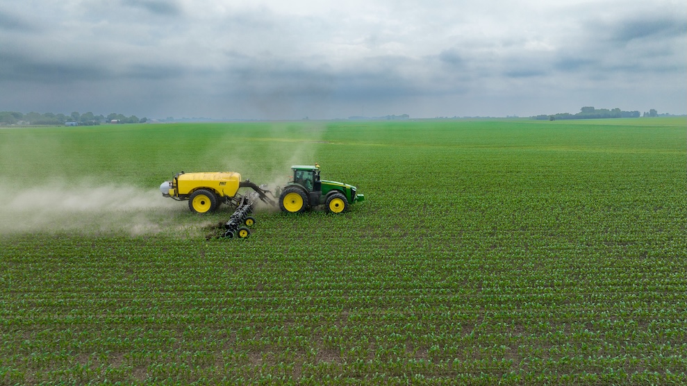 A tractor spraying a field, illustrating CBAM obligations for nitrogen fertiliser importers