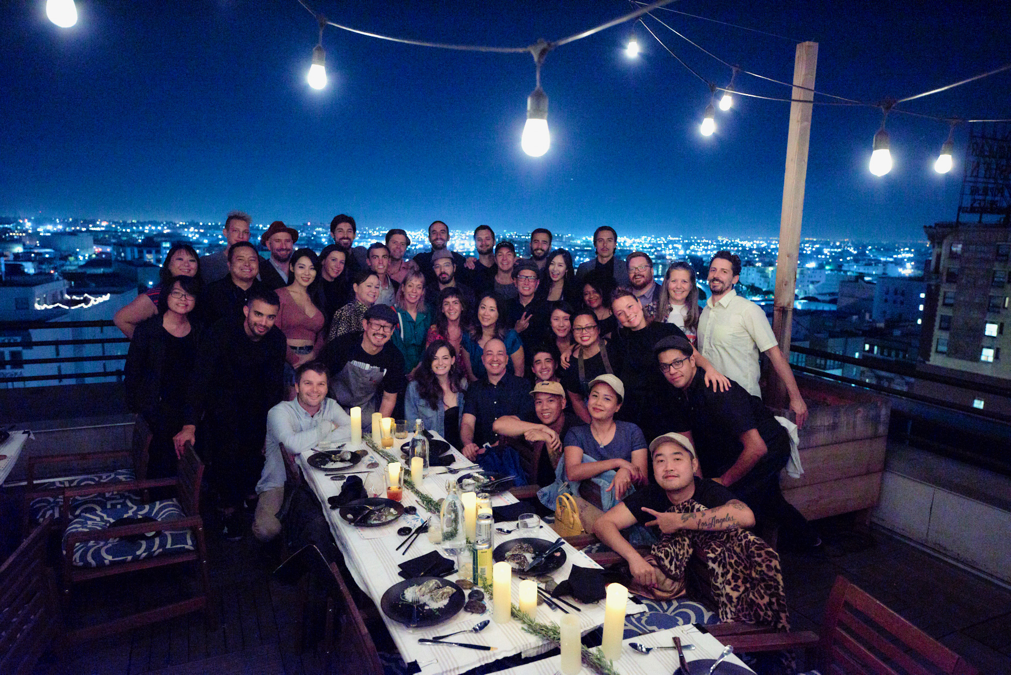 group photo of the DTLA Dinner Club on a rooftop with the LA night time skyline in the background