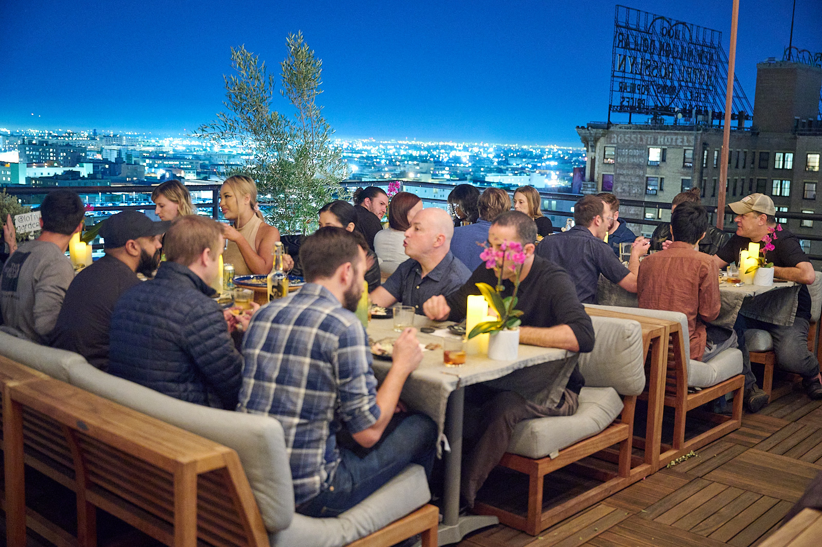 Guests at the DTLA Dinner Club enjoying a gourmet dinner with the LA night skyline behind them