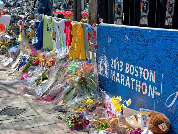 An image of the 2013 Boston Marathon memorial lined with bouquets of flowers.
