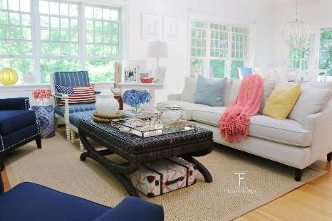 An image of the Brewster Residence designed by TFD of white sofa and 2 blue chairs and coffee table with windows and outdoor view in the background.