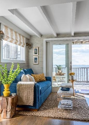 An image of a blue sofa and coffee table and side tables with ocean view background.