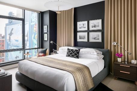 An image of Trevor Fulmer Design of modern elegance bedroom of wood platform bed and side table with city view in the background.