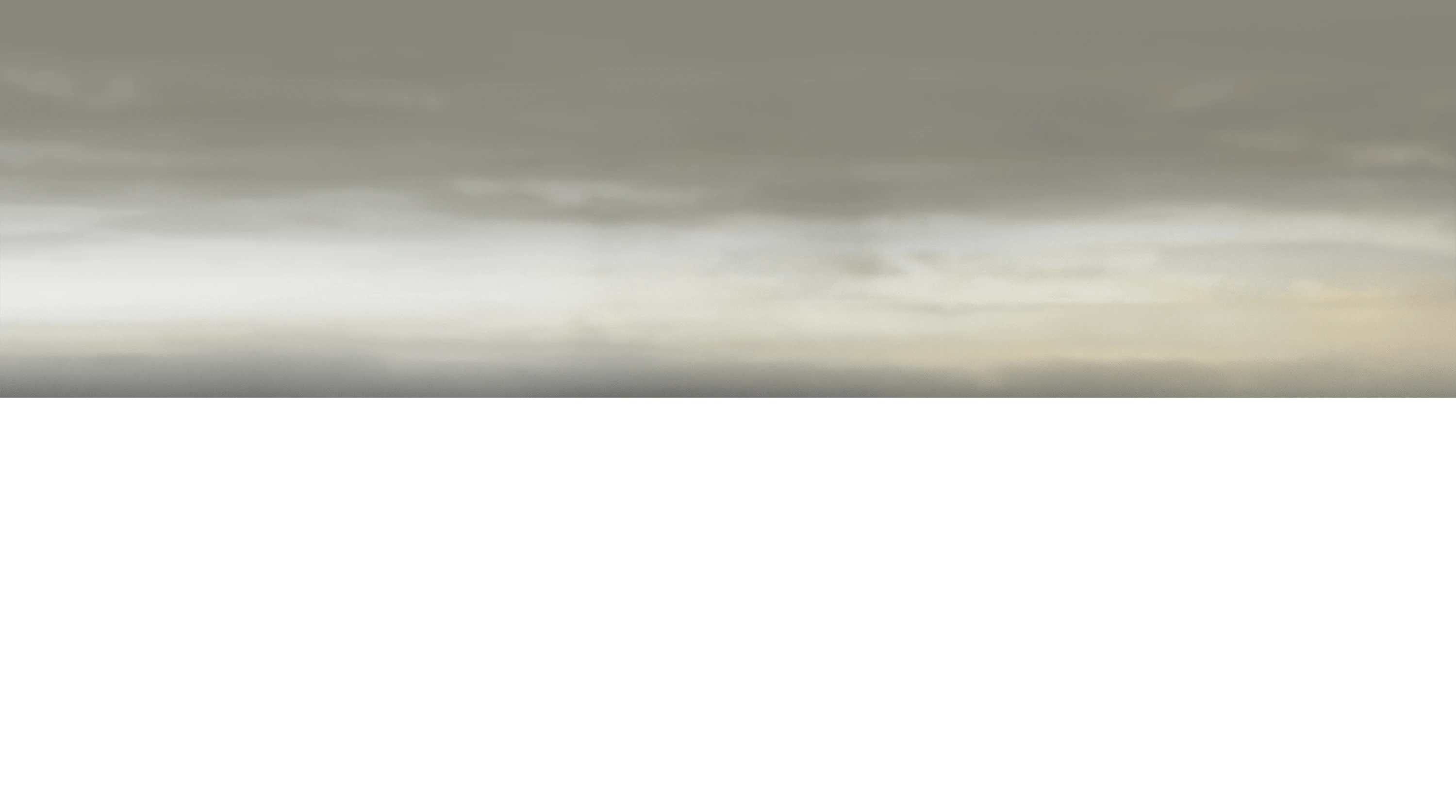 Hazy sky with overcast clouds in muted gray and beige tones.