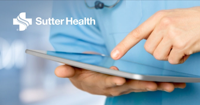 Close-up of a medical professional in blue scrubs holding and using a tablet device with the Sutter Health logo in the top left corner.