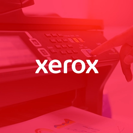 Finger pressing a button on a Xerox multifunction printer with documents partially visible below.