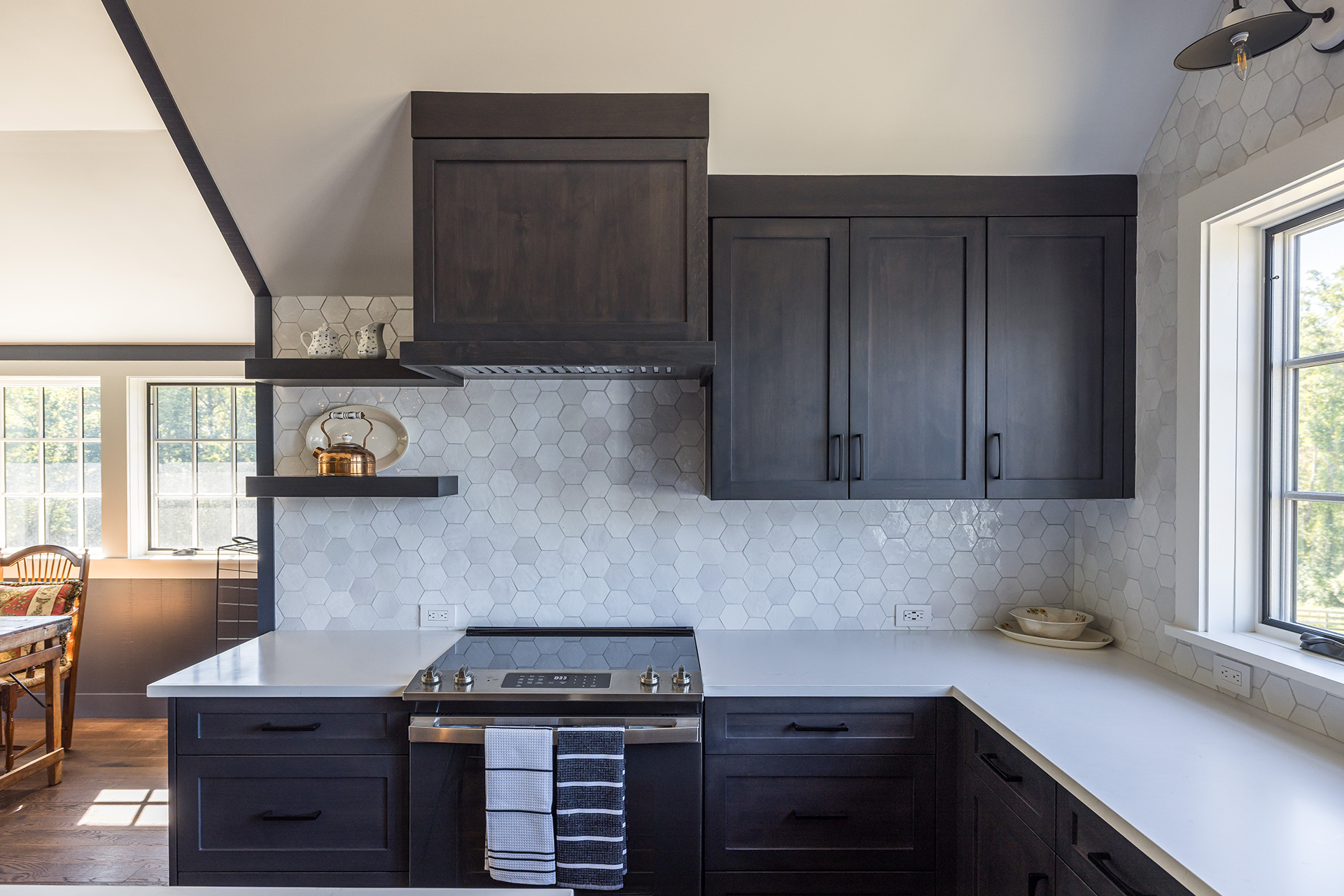 A custom kitchen featuring navy cabinets, white honeycomb tile, adorned with natural light, tucked within this barn living space.