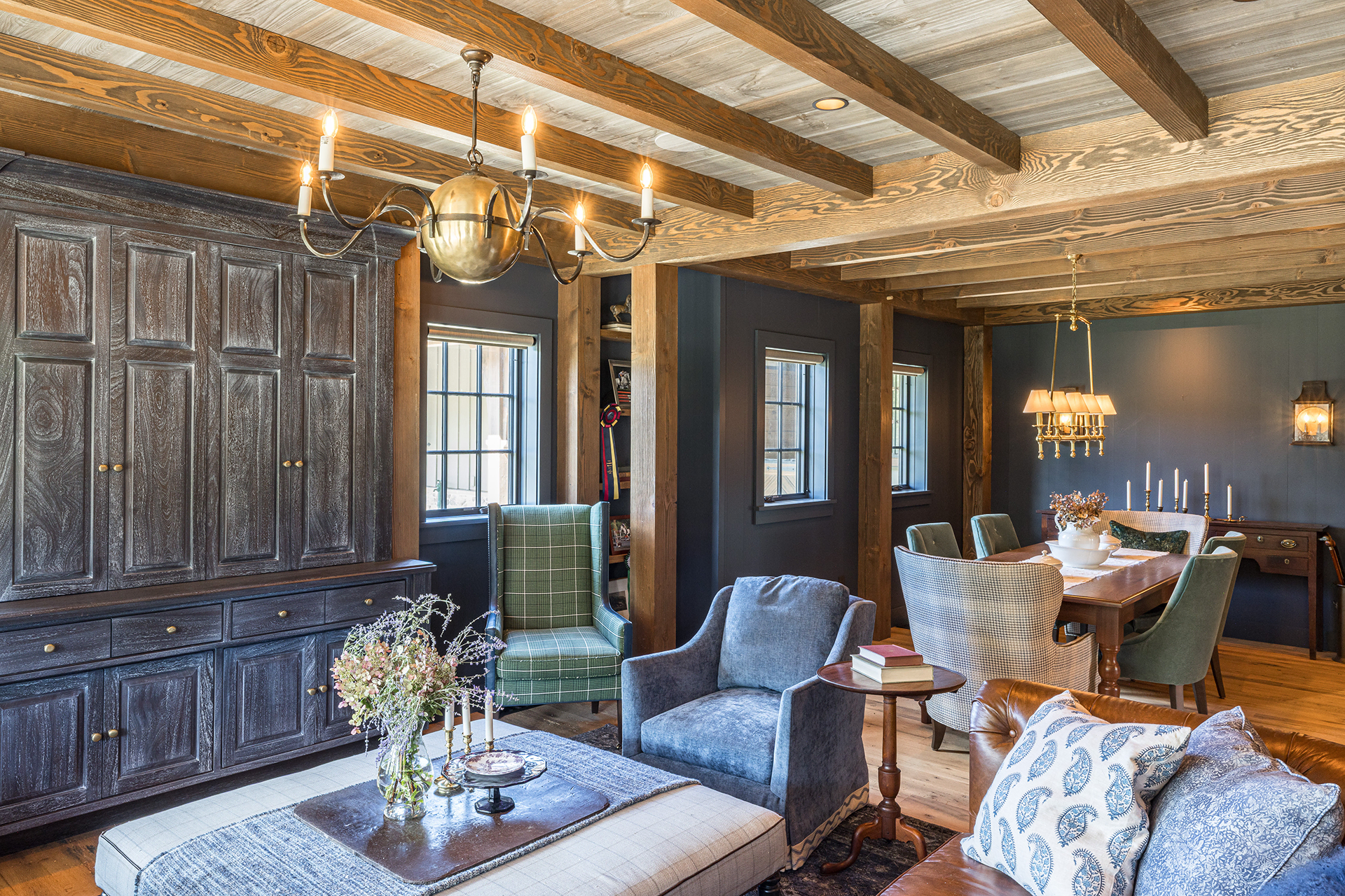 Timber frame lounge area featuring custom cabinets, wood floors, and layered brass lighting throughout the space.