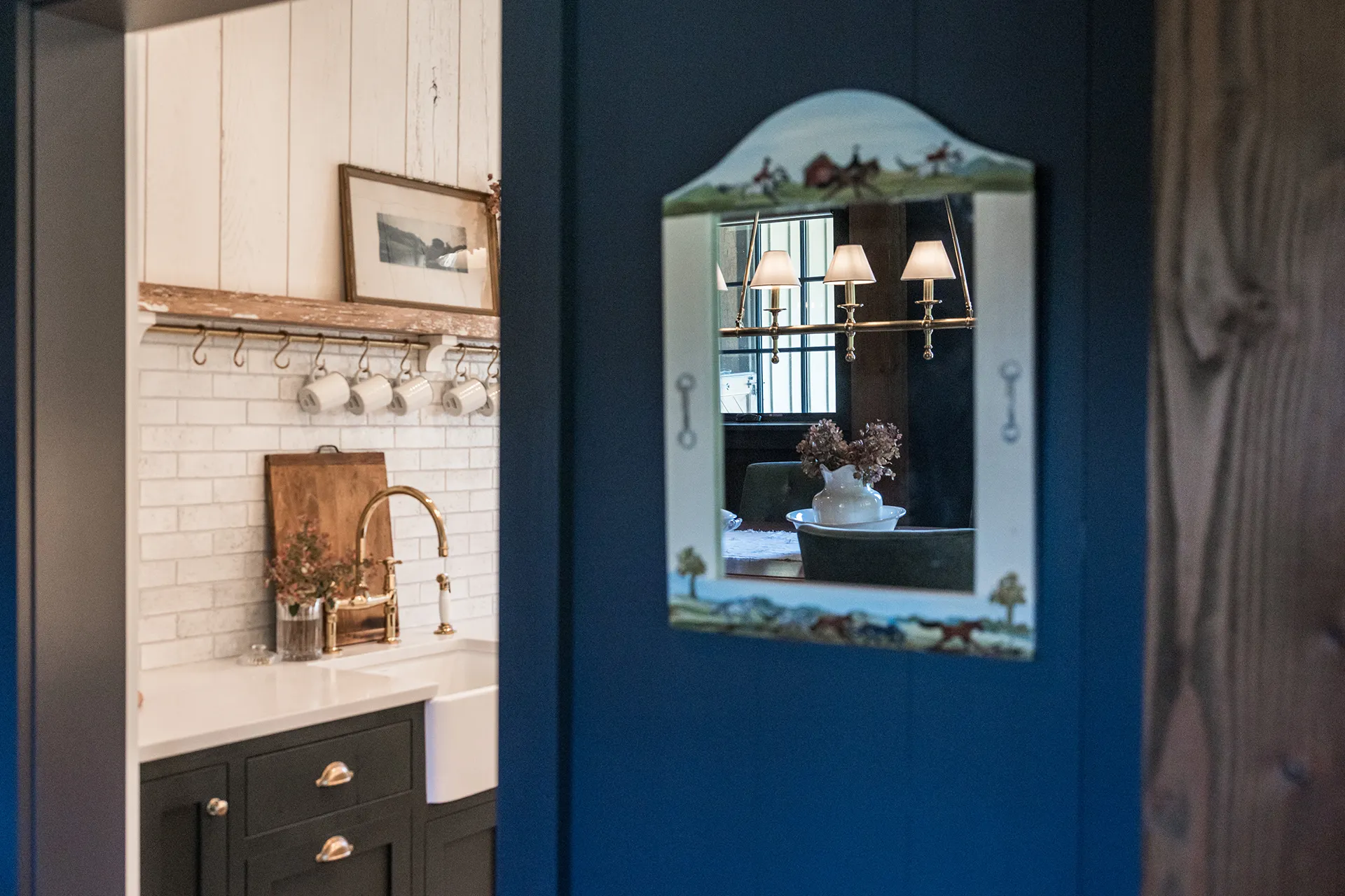 Charming kitchen corner in a horse barn, with an equestrian-themed mirror reflecting the living room with a brass chandelier.