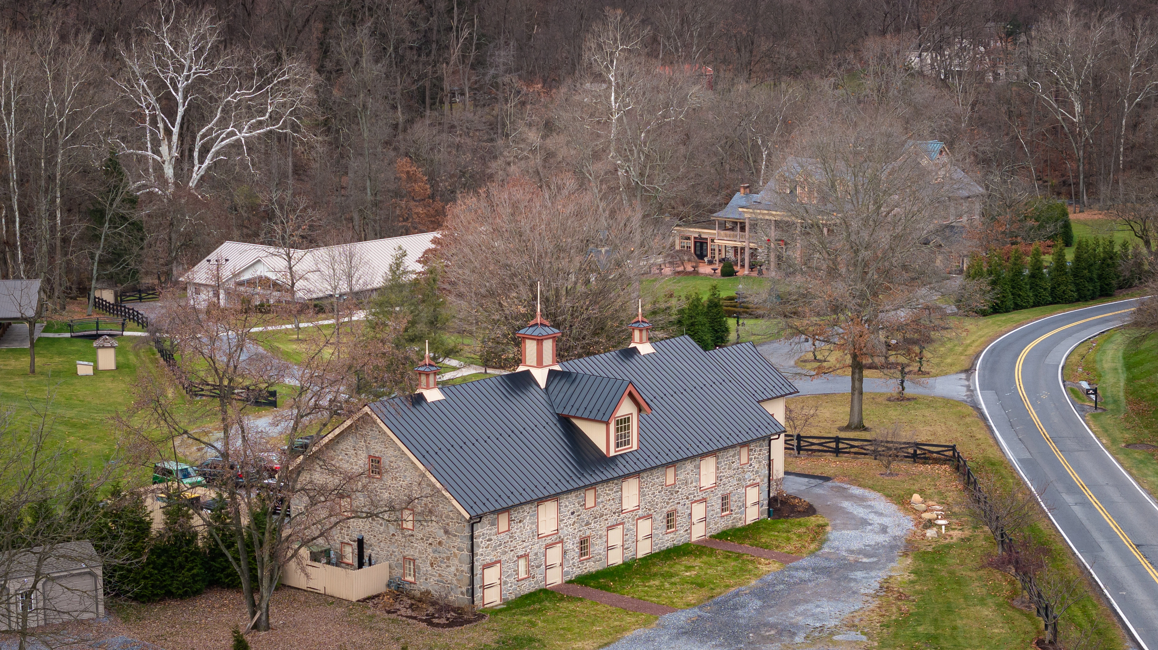 Aerial view of a historic barn restoration in Central Pennsylvania, with fieldstone walls and red-trimmed wood windows.