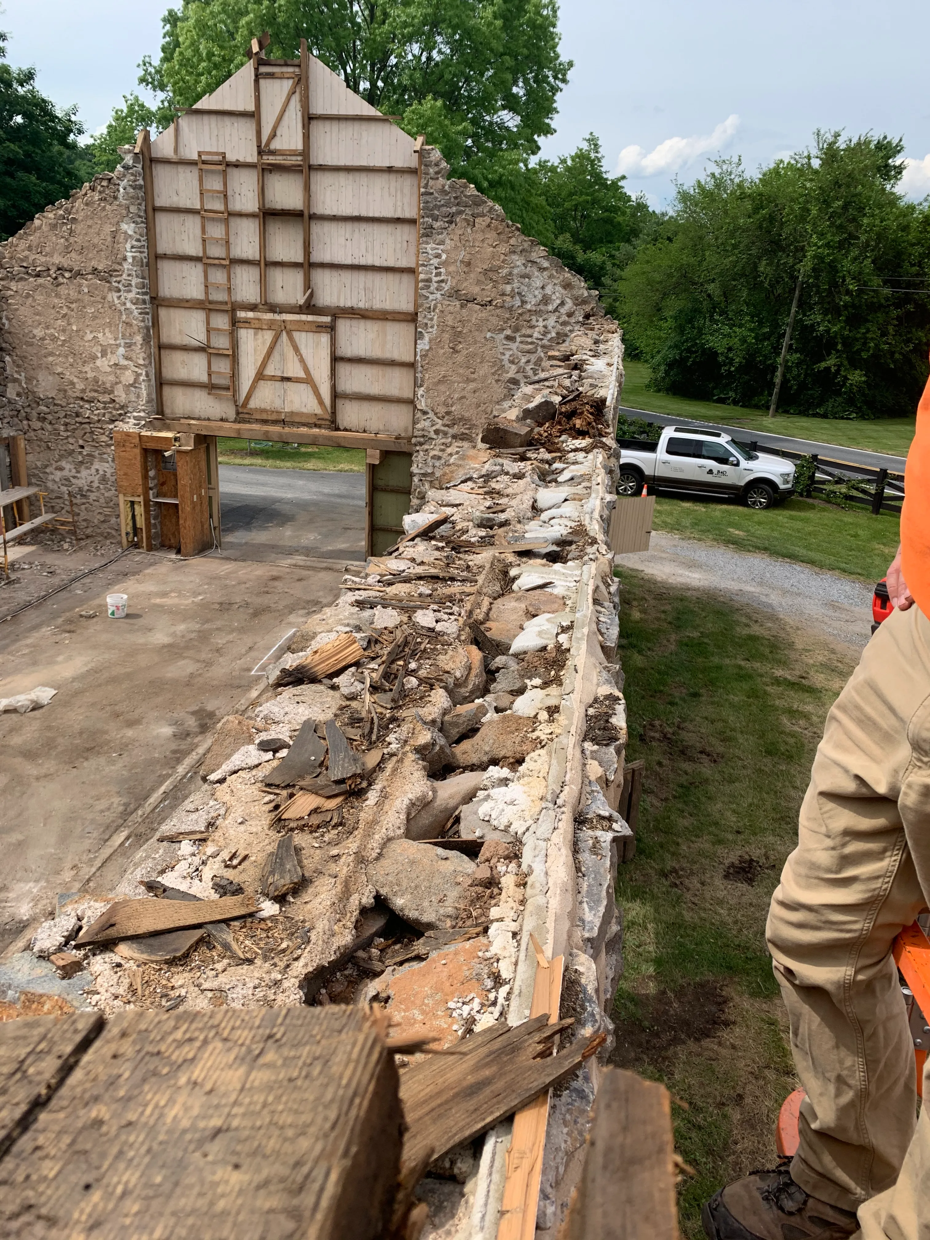 Historic Barn being in the middle of demolition with a missing roof and exposed fieldstone walls.