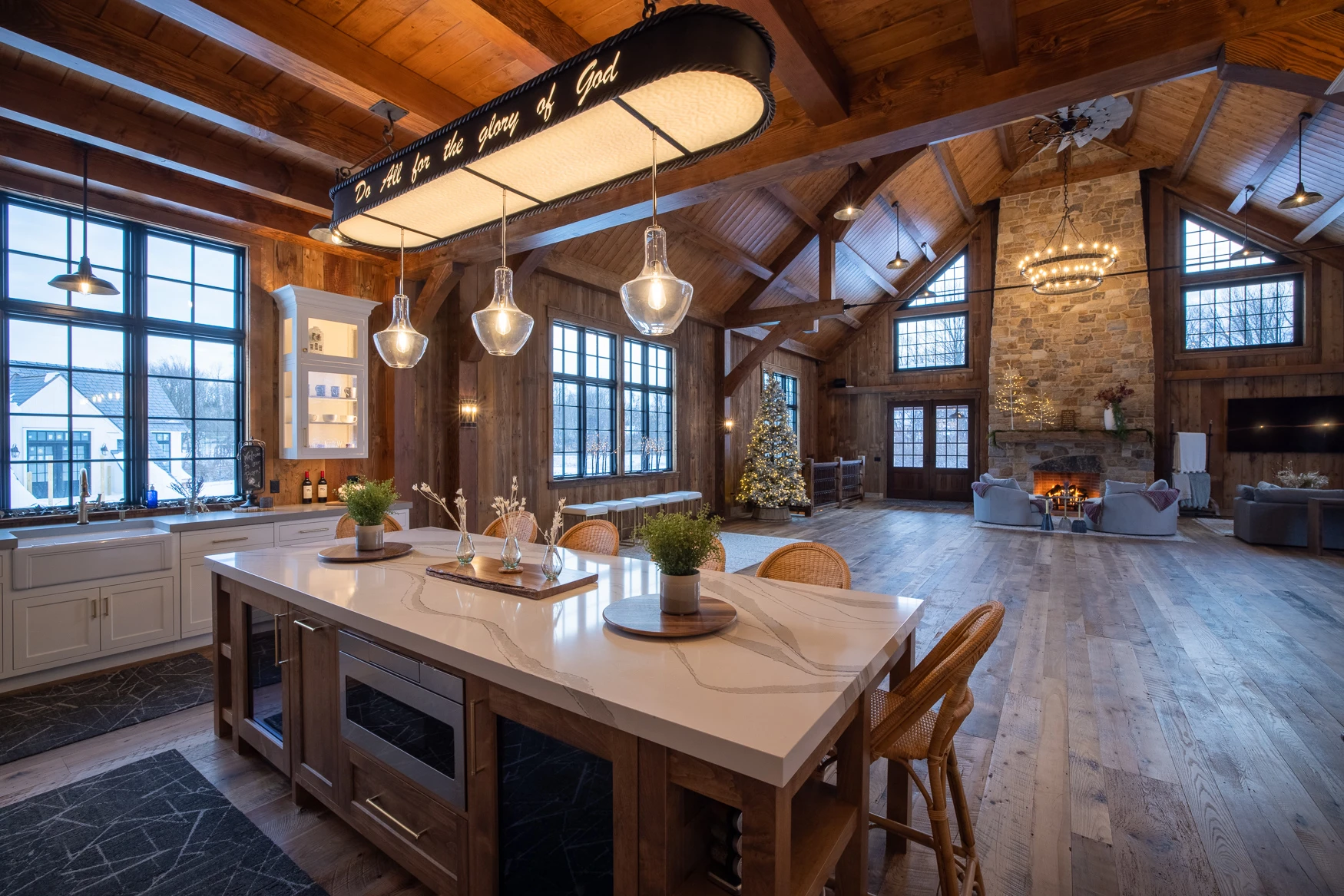 Open-concept timber frame party barn looking out from a kitchen with a center island and windows bringing in a lot of natural light.