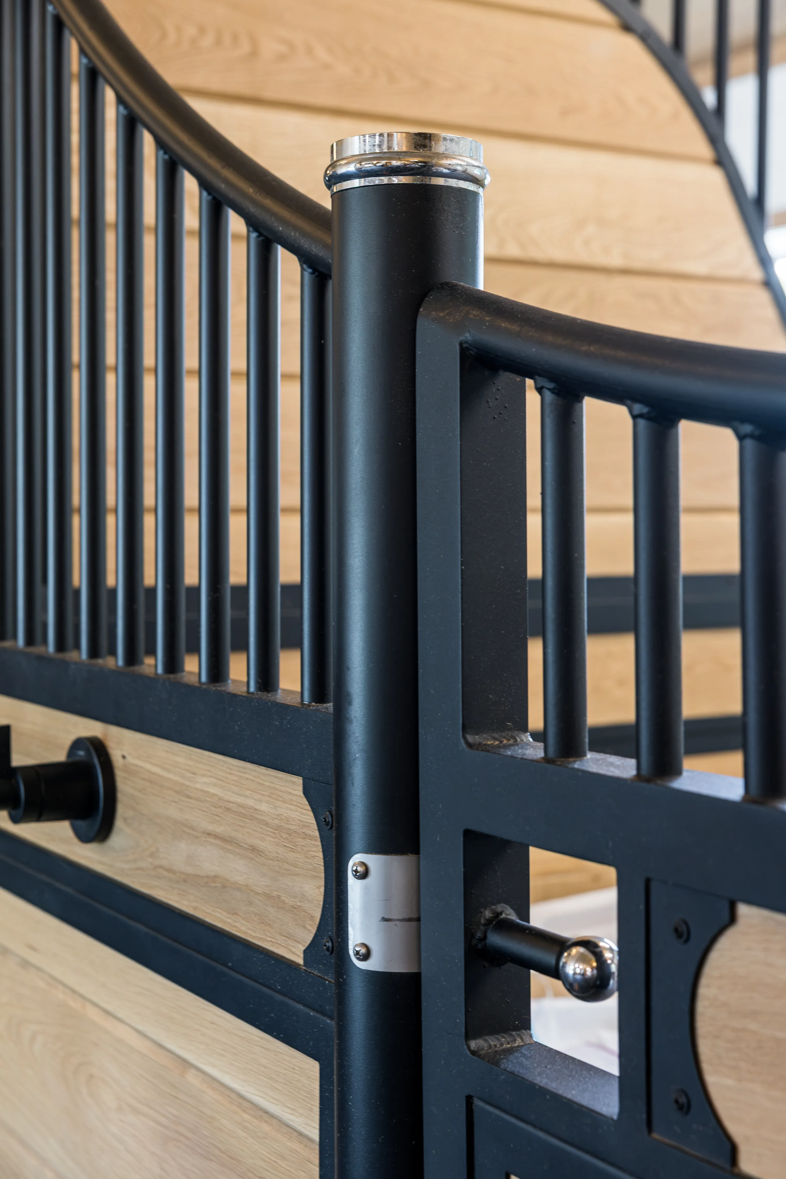 A close-up view of a custom stall front with matte black steel grills and frames and white oak wood inlays.