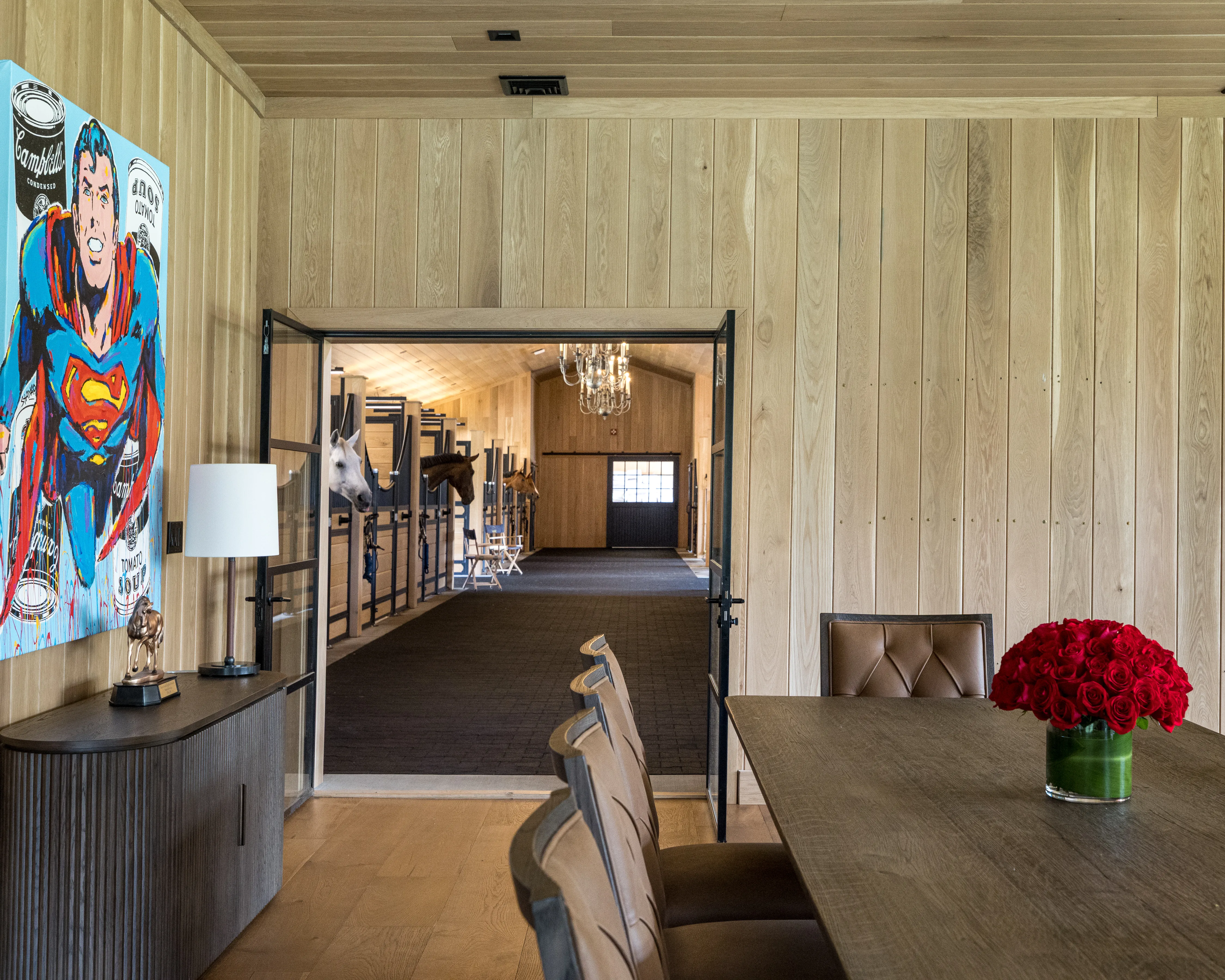 The doors in the owner’s suite open to the center aisle of this horse barn, where horses peer over their stalls in curiosity.