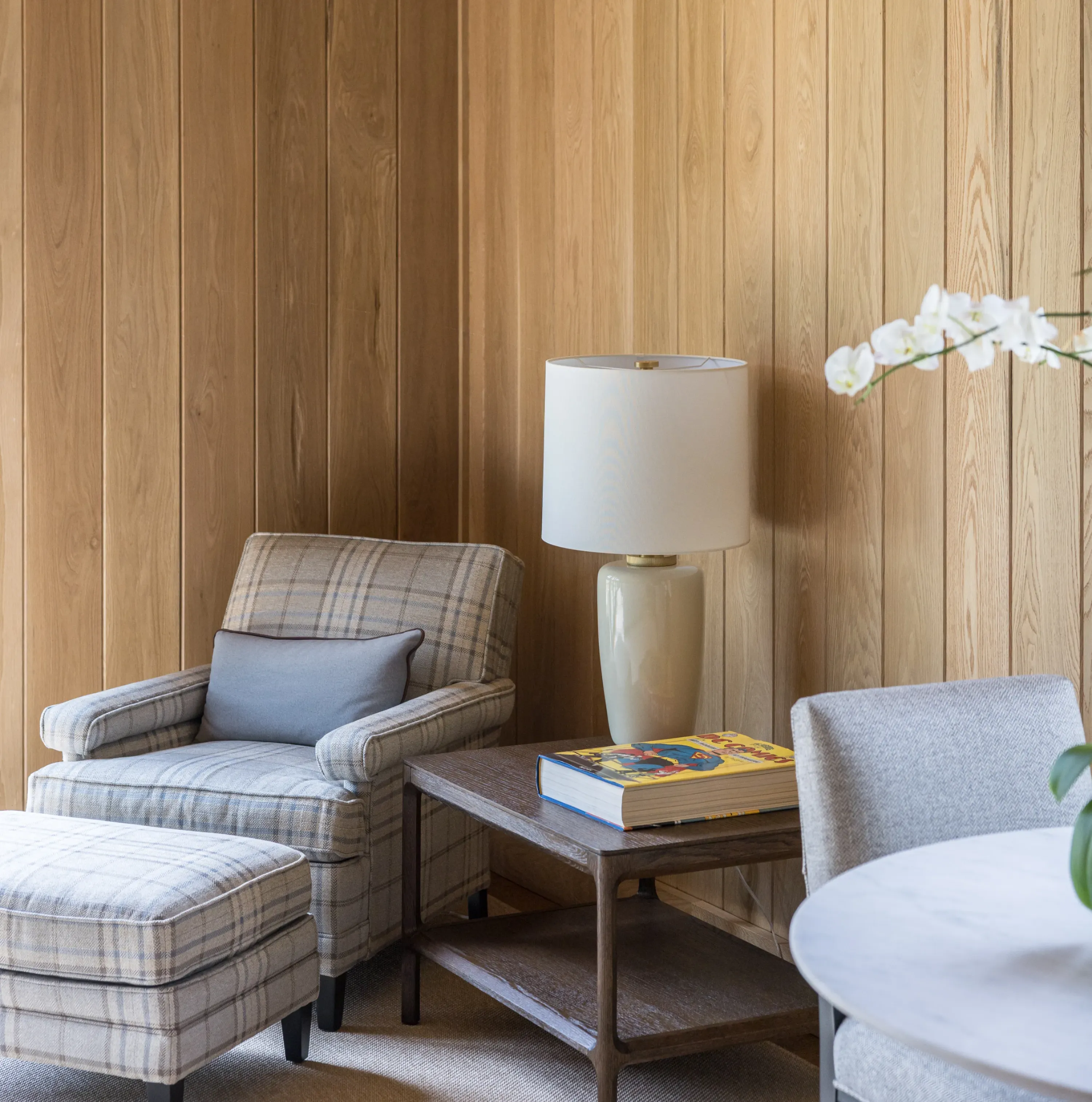 This cozy nook in the owner’s suite of this horse barn has comfortable furniture and a lamp sitting on a reclaimed wood end table.