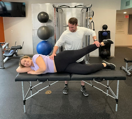 Physical therapist assessing hip abduction strength for HYROX athlete
