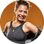 Smiling woman in athletic wear holding weights, posing confidently against white background.