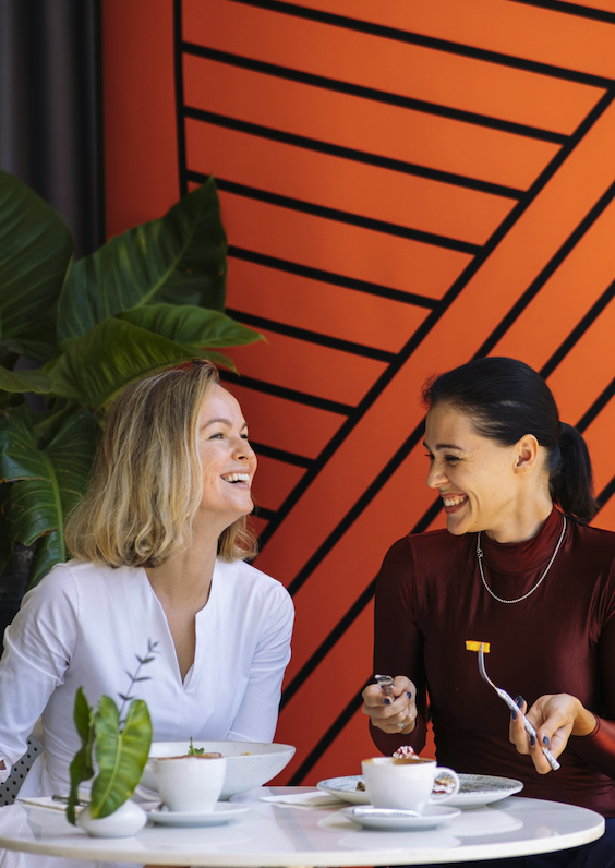 Two friends laughing over coffee and cake