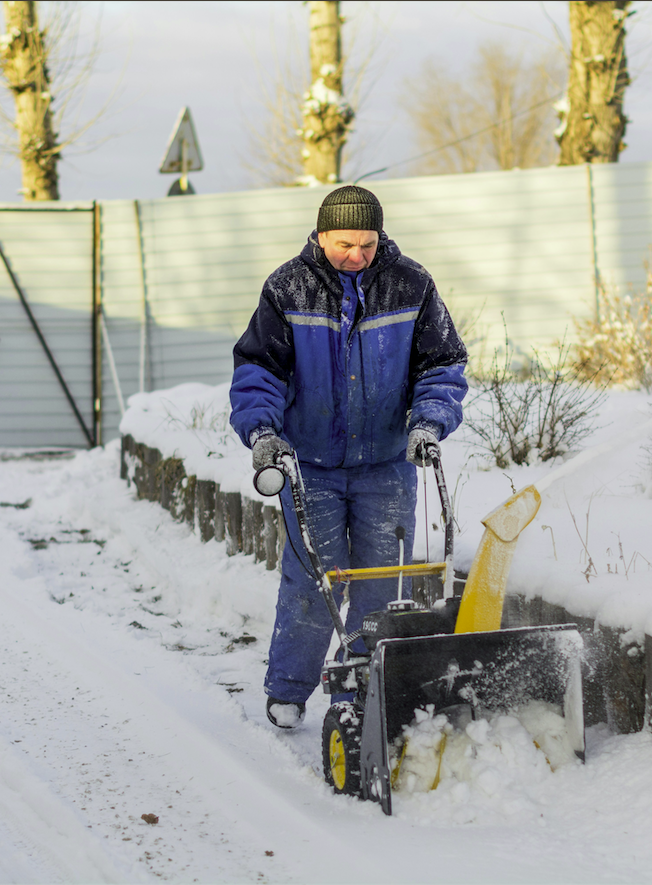 An older man clearing snow with a snowblower
