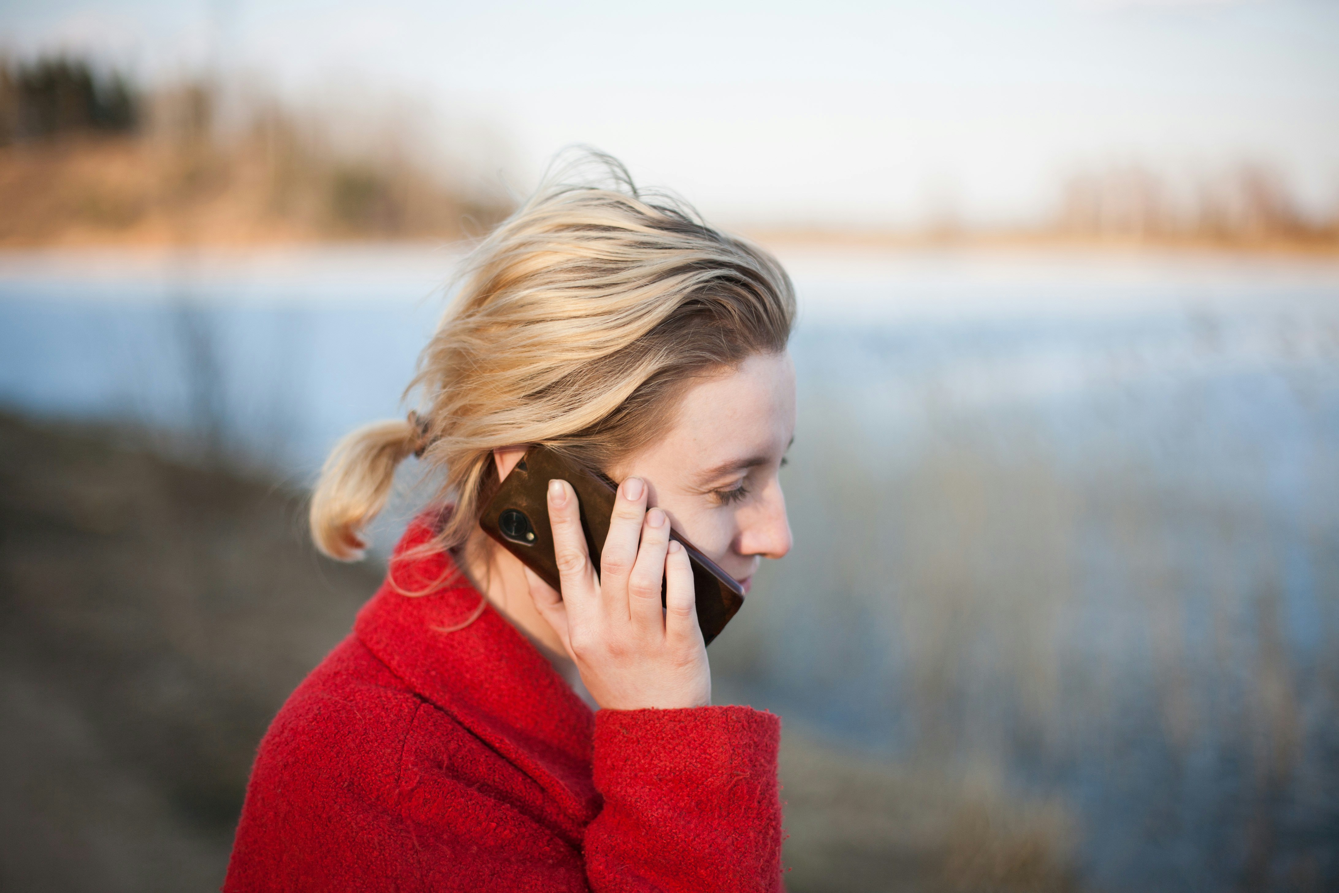 A woman in a red sweater on a phone call outdoors