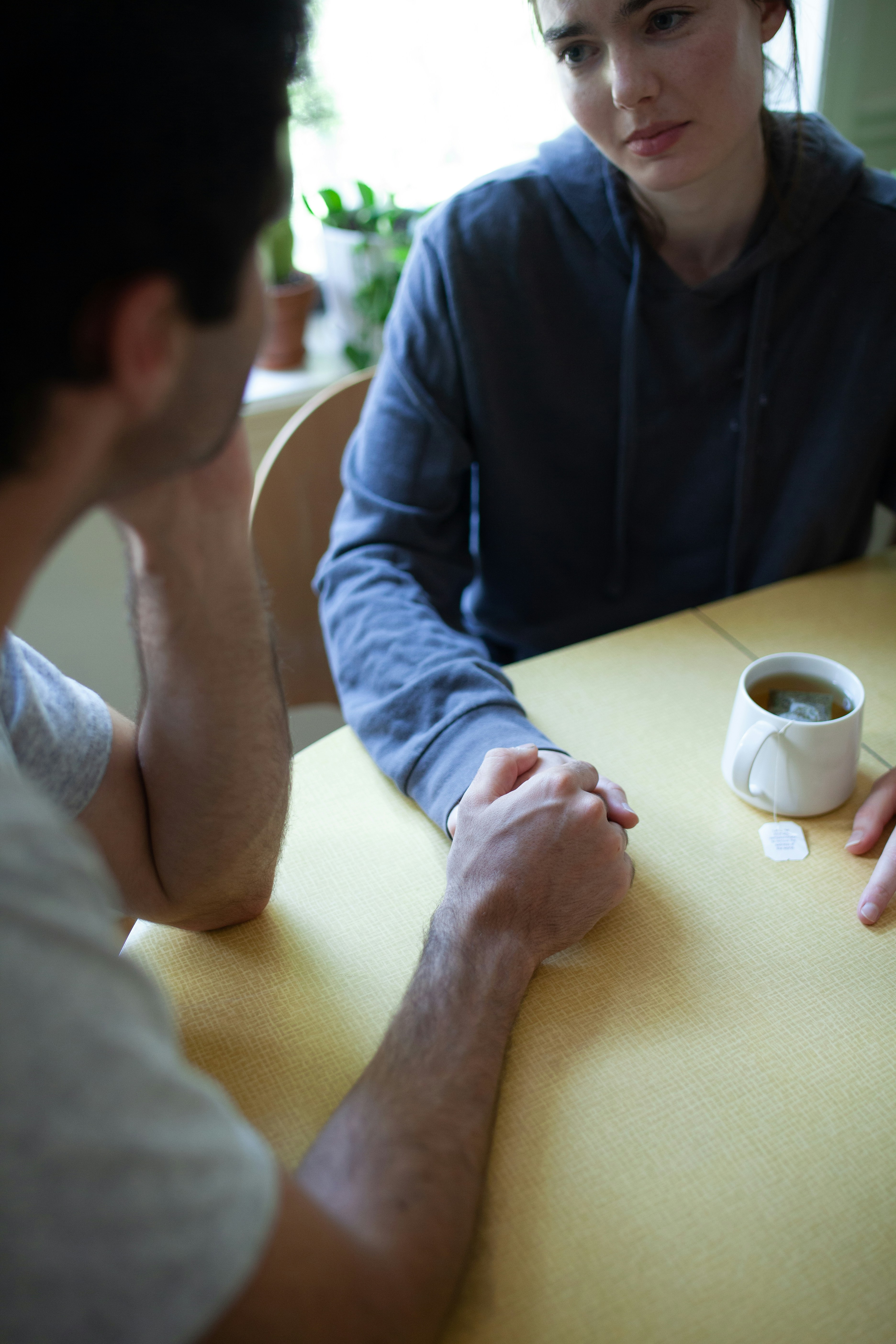 Two people talking things through over tea at the kitchen table