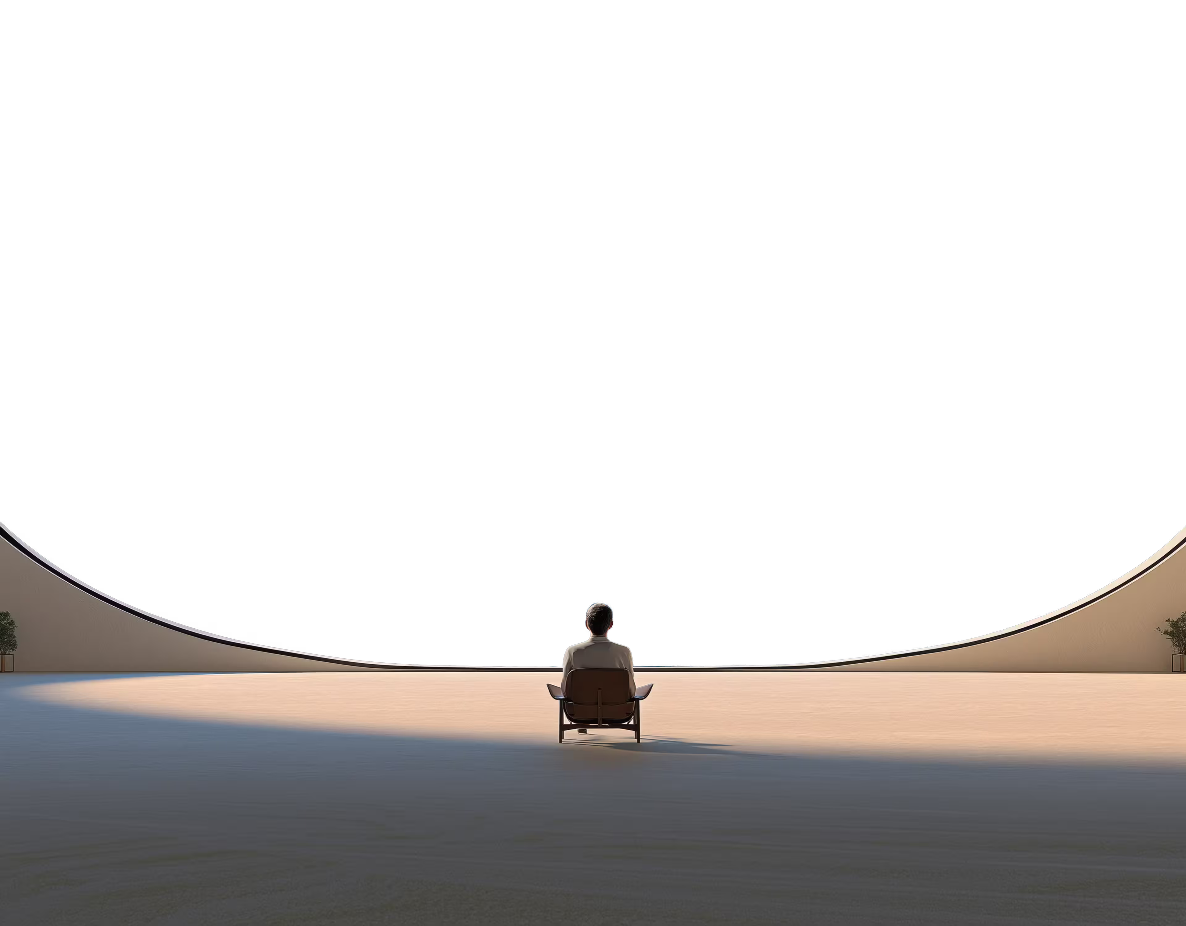 Person sitting on a chair alone in a large, minimalistic, curved space with light and shadows on the floor.