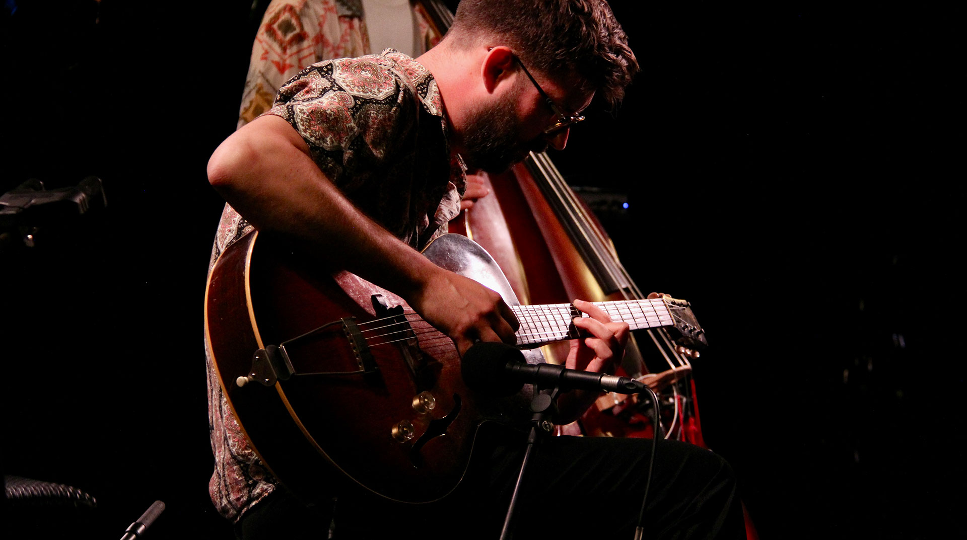 Musicien jouant de la guitare électrique dans une ambiance sombre de scène.
